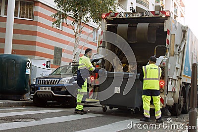 Two refuse collection workers loading garbage into waste truck emptying containers Editorial Stock Photo