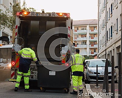 Two refuse collection workers loading garbage into waste truck emptying containers Editorial Stock Photo