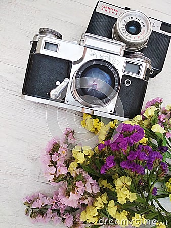 Two retro cameras with flowers on a light wooden background. Editorial Stock Photo