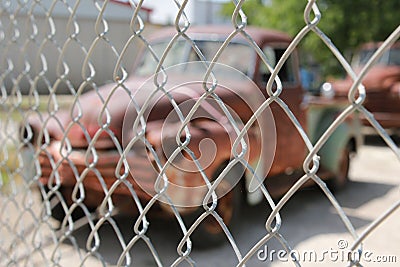 Two retro, rusted pick-up trucks behind chain link fence Stock Photo