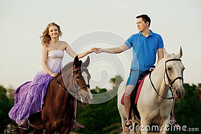 Two riders on horseback at sunset on the beach. Lovers ride horseback. Young beautiful man and woman with a horse at the sea. Rom Stock Photo