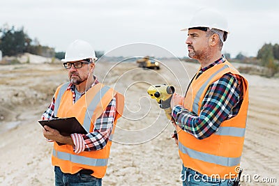 Road construction workers using measuring device on the field Stock Photo