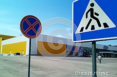 Two road signs on a background of a shopping center and blue sky. Editorial Stock Photo