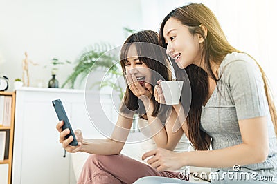 Two roommates using their smart phones sitting on a sofa at home Stock Photo