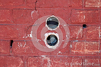 Two round electrical outlet boxes without wires mounted inside dilapidated red brick wall Stock Photo