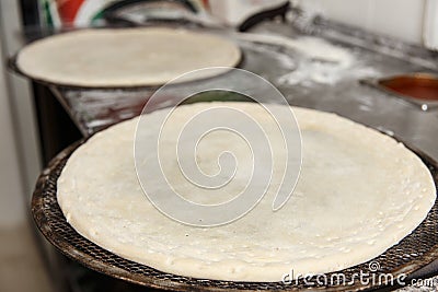 Two round raw pizza bases lies on a metal grid Stock Photo