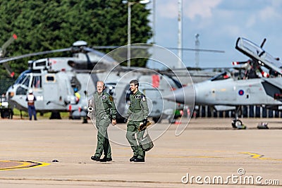 Two Royal Air Force Pilots walking across the tarmac at RAF Waddington with aircraft sitting in the background. Editorial Stock Photo