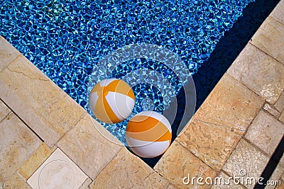 Two rubber air yellow white inflatable balls and toy for swimming pool in transparent blue water. Beach balls floating on water. Stock Photo