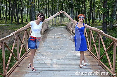 Two Russian sisters holding hands and sincerely laughing with natural laugh on a summer day Stock Photo