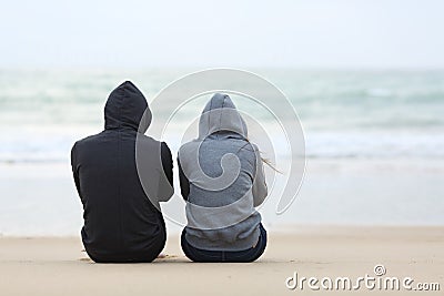 Two sad teenagers sitting on the beach Stock Photo