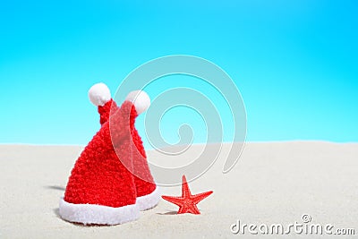 Two Santa hats next to a starfish on a sunny beach Stock Photo