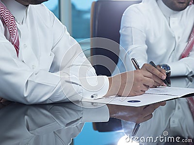 Two Saudi Businessmen Hands Signing A Ducument Stock Photo