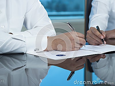 Two Saudi Businessmen Hands Signing A Ducument Stock Photo