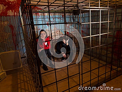 Two scared Halloween victims imprisoned in a metal cage Stock Photo