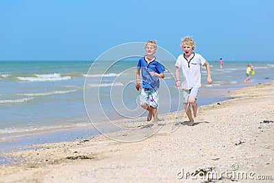 Two school boys running on the beach Stock Photo