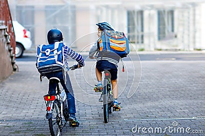 Two school kid boys in safety helmet riding with bike in the city with backpacks. Happy children in colorful clothes Stock Photo