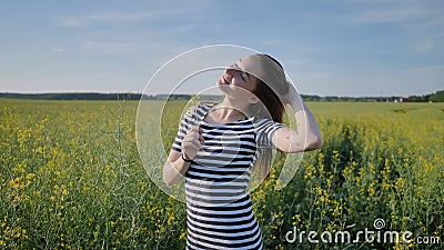 Schoolgirl posing with flowers in a rapeseed field. Stock Photo