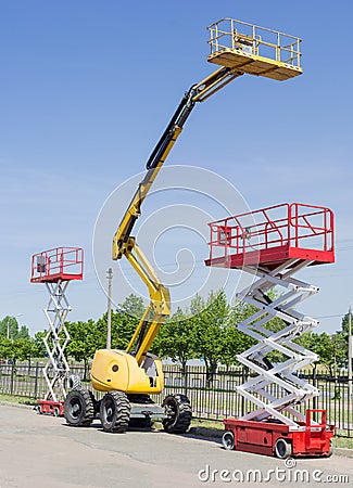 Two scissor and one articulated boom lift on asphalt ground Stock Photo