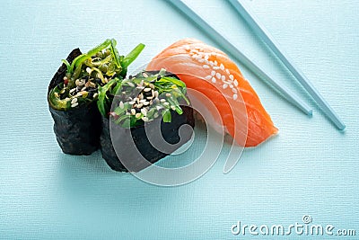 Two seaweed Sushi Chuka and sushi nigiri with salmon with chopsticks on a blue Stock Photo