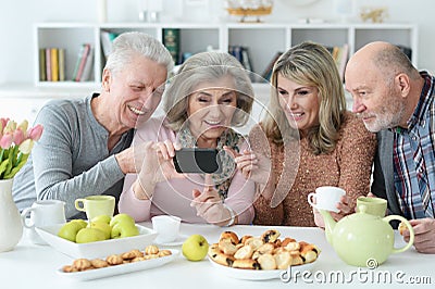 Two senior couples using smartphone during morning tea Stock Photo