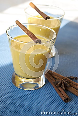 Two servings of golden milk in transparent glasses on a blue background, with spice Stock Photo