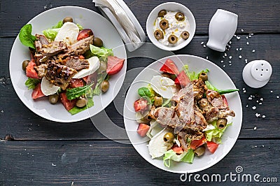 Two servings of grilled meat and salad with vegetables, mozzarella and herbs. Traditional Mediterranean Cuisine Stock Photo