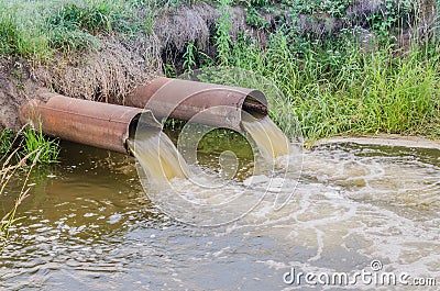 Two sewer pipes pour out to the river/water gushing from the sewer to the river Stock Photo