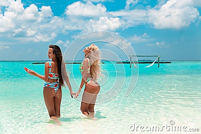 Two sexy bikini models having fun on tropical beach, exotic Maldives island. Summer vacation. Happy smiling women in fashion Stock Photo