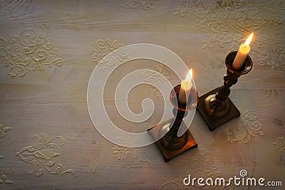 two shabbat candlesticks with burning candles over wooden table. top view. low key Stock Photo