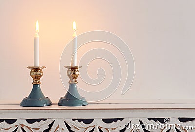 Two shabbat candlesticks with burning candles over wooden table Stock Photo