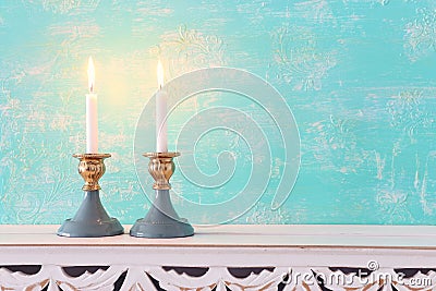 Two shabbat candlesticks with burning candles over wooden table Stock Photo