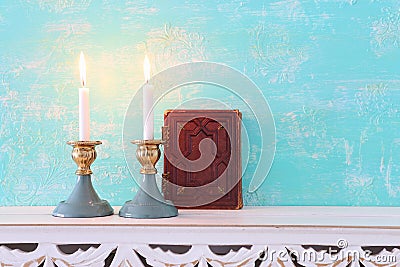 Two shabbat candlesticks with burning candles over wooden table Stock Photo