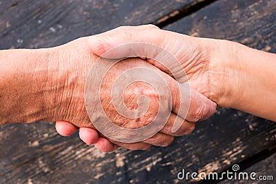 Two shaking hands. Love and friendship concept. Aid for old people. Trust and security for elderly. Caucasian human hands on black Stock Photo
