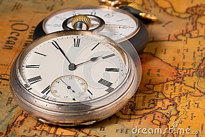 Two silver retro pocket watches lying on an old paper map of the world. Antique gray round clock with a dial and hands Stock Photo