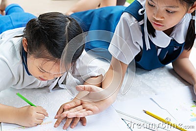 Two sister girl writes to writing-books. The decision of lessons. girl lay down drawing the picture Stock Photo