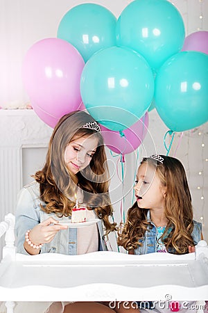 Two sisters with cake and balloons, birthday concept Stock Photo