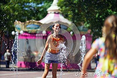 Two sisters playing with fountain splash Stock Photo