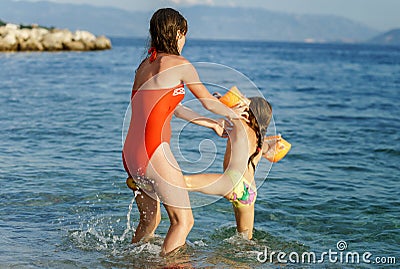 Two sisters playing games and swimming in the sea Stock Photo