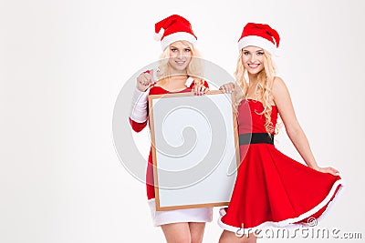 Two sisters in santa claus costumes posing with blank board Stock Photo