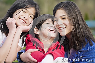 Two sisters and their disabled little brother Stock Photo