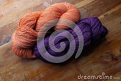 Two skeins of richly colored yarn on orange and deep purple, knitting and crochet, old wooden table top background Stock Photo