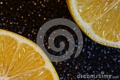 Two sliced yellow lemons on a shimmering dark background. Ingredient for party cocktails and other drinks. Glowing bokeh of stars Stock Photo