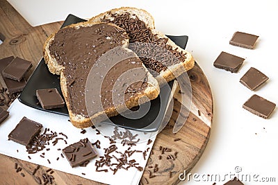 Two slices of bread on wooden plate with chocolate pasta and hail, Dutch hagelslag Stock Photo