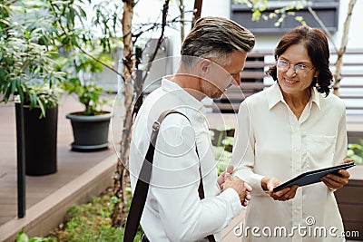 Two smiling business parthners using tablet while standing outdoors Stock Photo