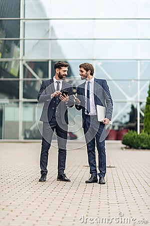 Two smiling businessman colleagues in a blue suit talking and walking business people discussing strategy Stock Photo