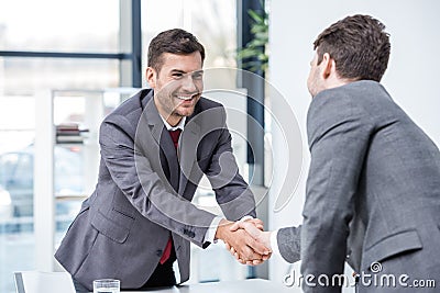 Two smiling businessmen shaking hands at meeting in office Stock Photo