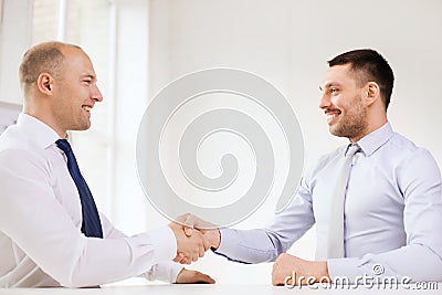 Two smiling businessmen shaking hands in office Stock Photo