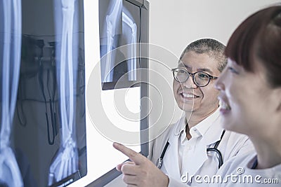 Two smiling doctors looking at x-rays of human bones, pointing Stock Photo
