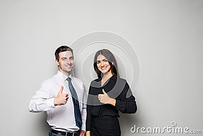 Two smiling happy businesspeople in formalwear showing thumbs-up on gray Stock Photo