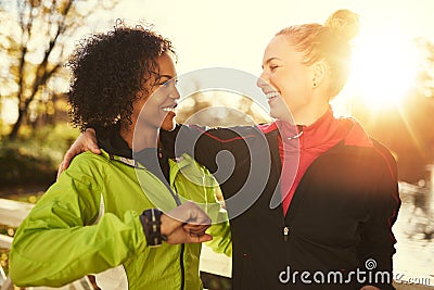 Two smiling sportswomen hugging while standing outdoors Stock Photo